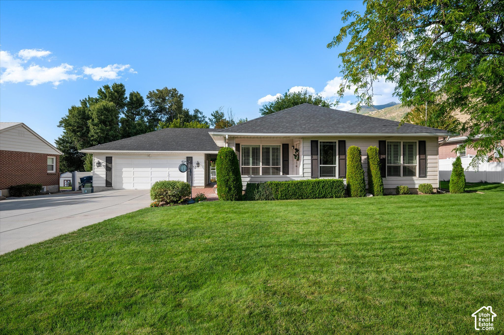 Expansive front lawn, attached two-car garage, mature trees, and landscaping