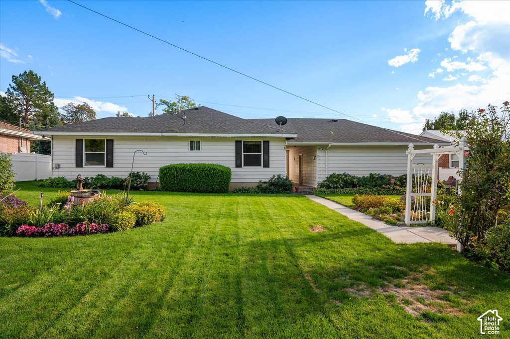White horizontal siding exterior with dark shutters, dark shingle roof, green lawn, and established landscaping