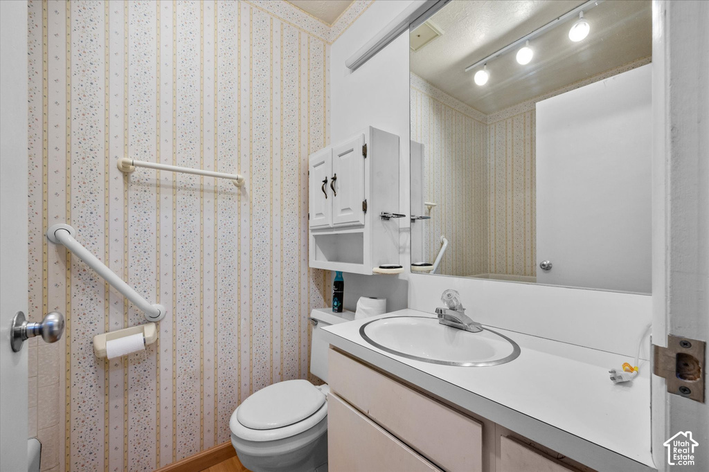 White vanity with integrated sink, wall-mounted mirror, track lighting, and built-in wall cabinet