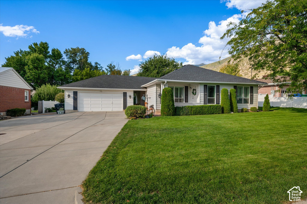 Single-story residence featuring a two-car garage, concrete driveway, and front lawn