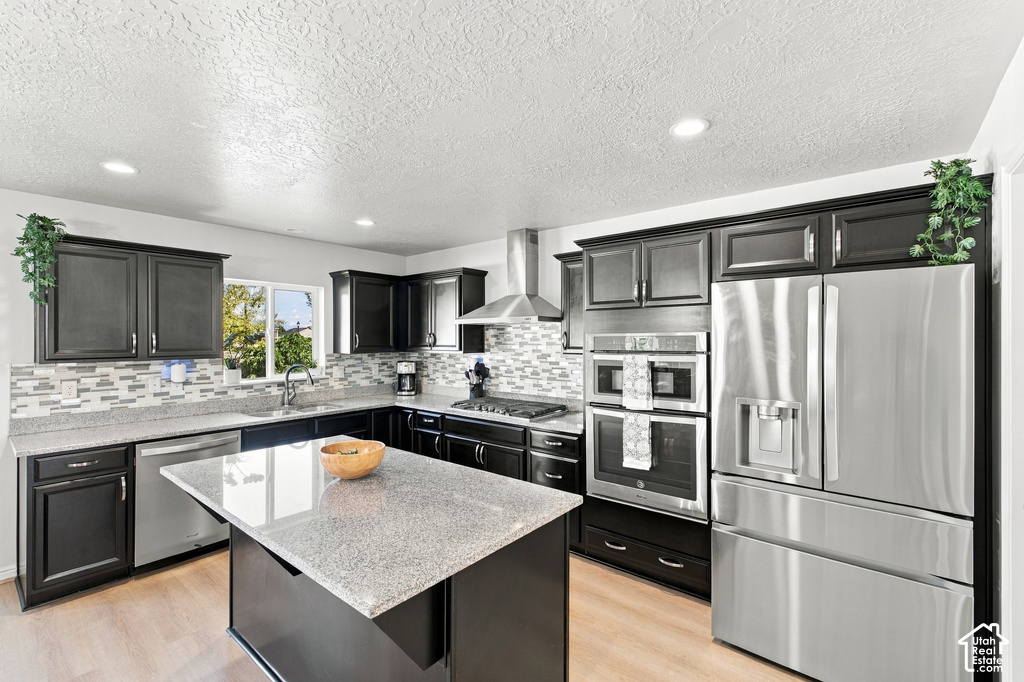 Kitchen featuring dark wood cabinetry, light-toned countertops, stainless steel appliances, a tiled backsplash, and recessed lighting