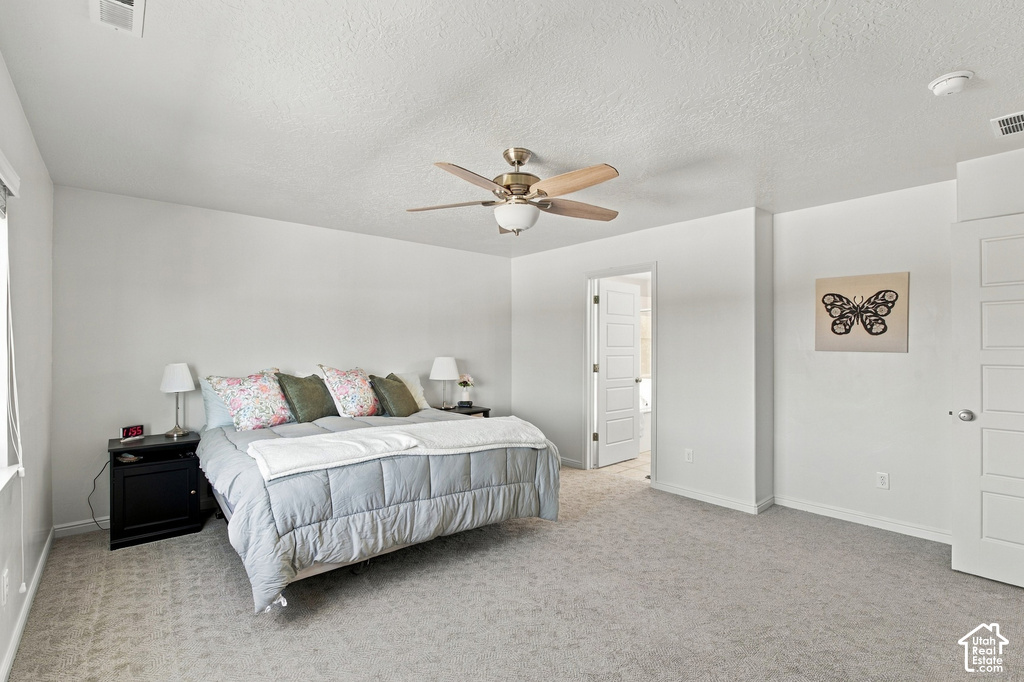 Spacious bedroom featuring light-colored carpet, white walls, and a ceiling fan