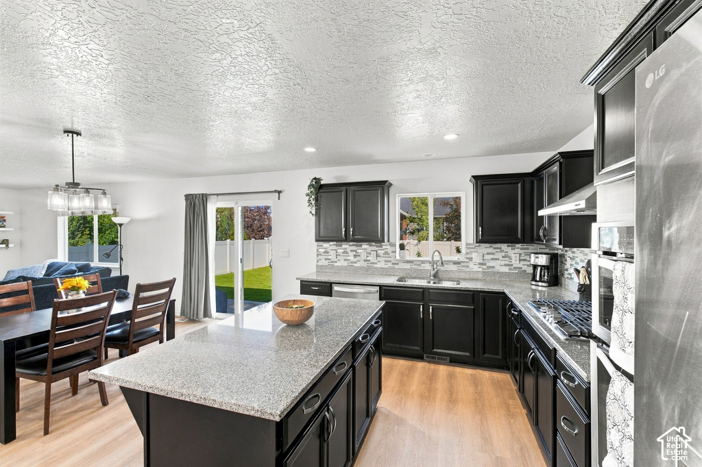 Kitchen featuring dark wood cabinetry, light-toned countertops, a tile backsplash, and stainless steel appliances