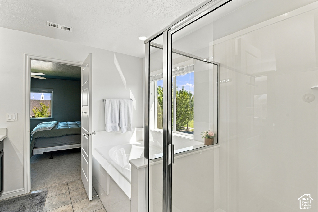 Glass-enclosed shower with sliding door, built-in bathtub, and window with outdoor scenery