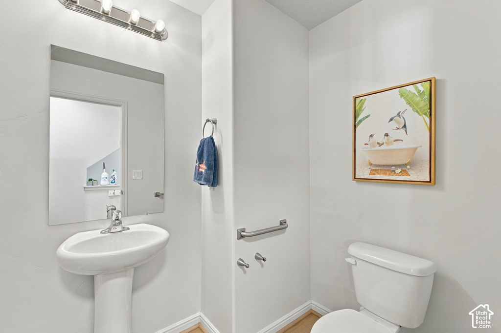 Pedestal sink with chrome faucet, wall-mounted mirror, and overhead vanity lighting