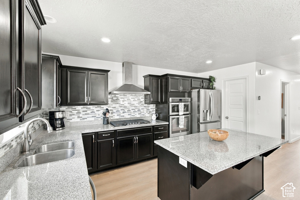 Kitchen featuring dark wood cabinetry, light-colored countertops, a tile backsplash, stainless steel appliances, and a central island