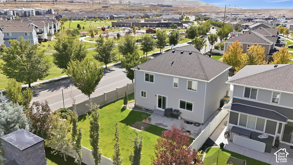 Rear exterior featuring a patio, manicured lawn, and mature trees