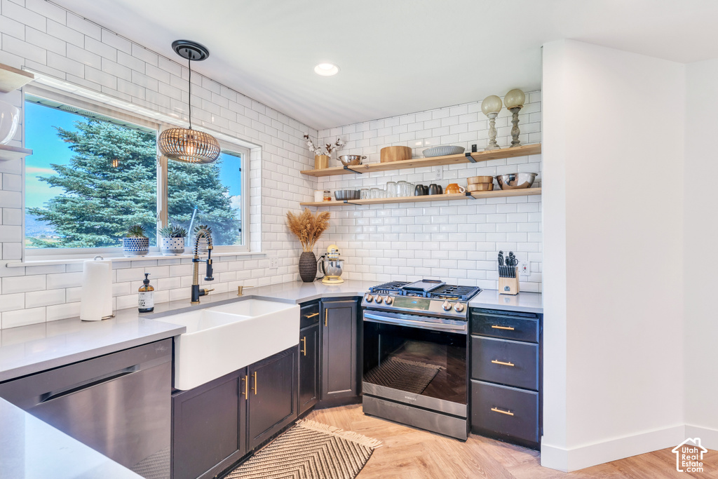Kitchen featuring a farmhouse sink, stainless steel appliances, white subway tile backsplash, wood-finish flooring, and open shelving