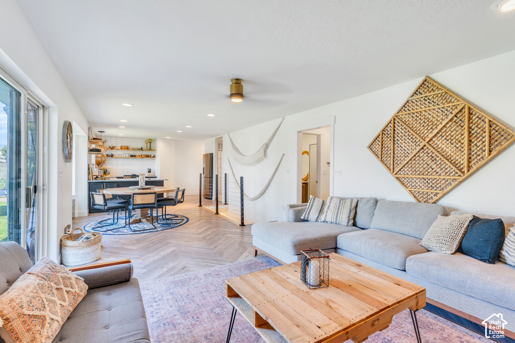 Open-concept living space with herringbone wood-finish flooring, recessed lighting, and a modern kitchen featuring open shelving