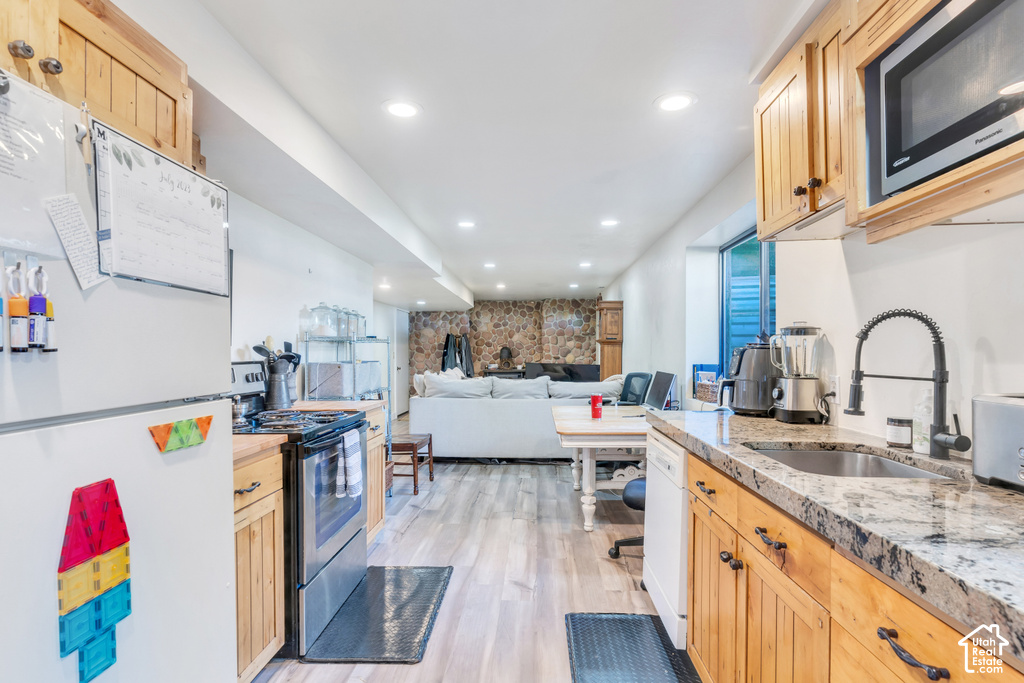 Kitchenette with light wood-finish cabinetry, stone-finish countertops, and a stainless steel sink