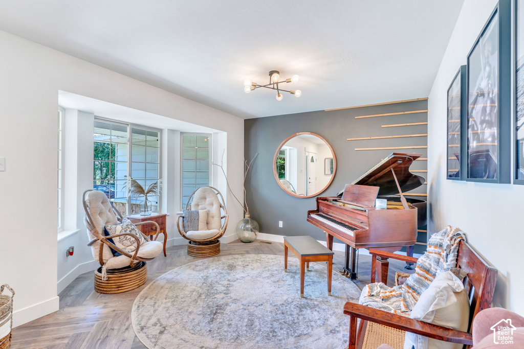 Bay window, wood-finish flooring, accent wall with horizontal wood trim, modern ceiling light fixture, and framed wall art