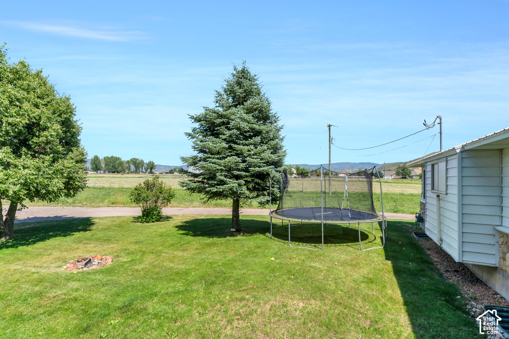 Expansive grassy yard with mature trees and a built-in fire pit
