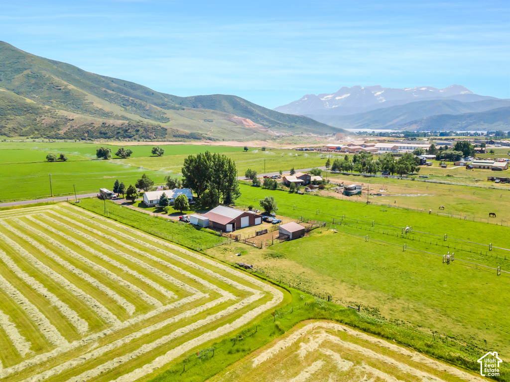Expansive agricultural landscape featuring prepared fields, multiple outbuildings, and a main residence, set against a backdrop of rolling hills and distant mountains