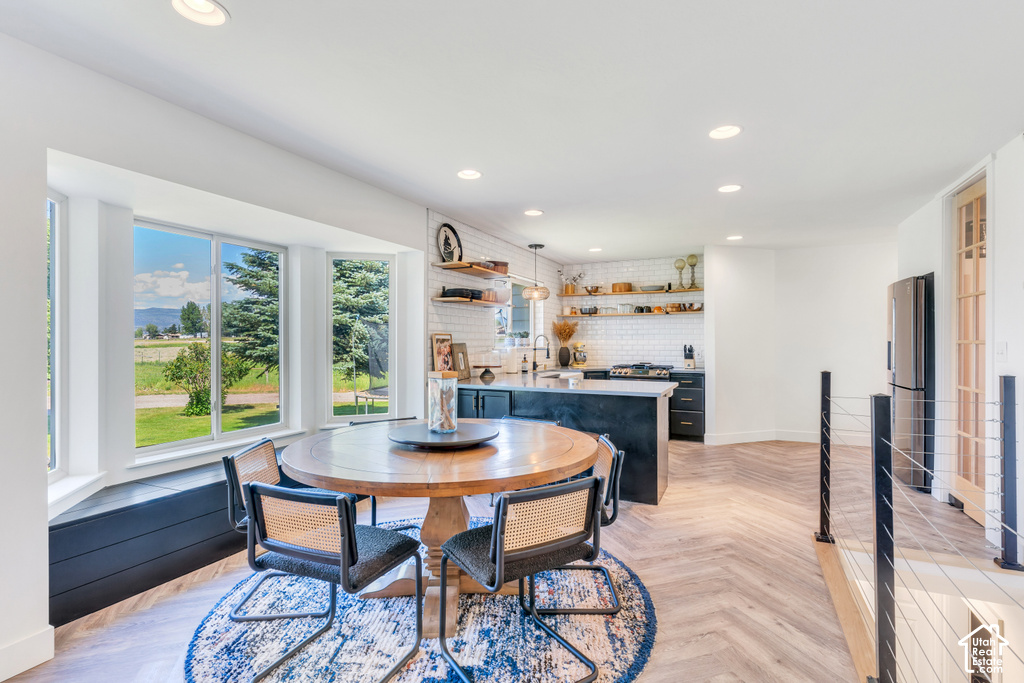 Open-concept living space featuring a bay window with integrated seating, herringbone wood-finish flooring, and recessed lighting
