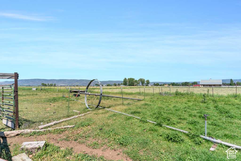 Expansive open field with a metal gate, perimeter fencing, and a visible irrigation system