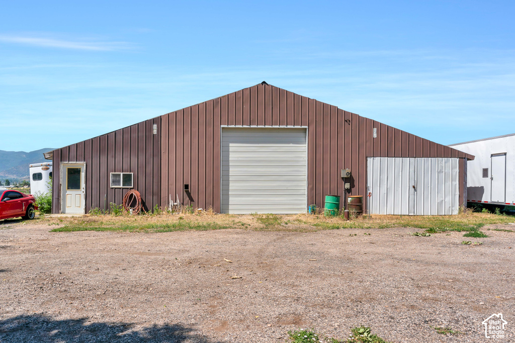 Metal-sided structure featuring a large roll-up door, a standard entry door with a window, and an additional set of double doors