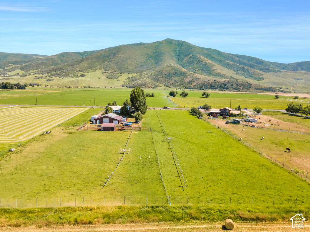 Extensive green acreage, surrounding mountainous landscape, multiple structures, and agricultural fields