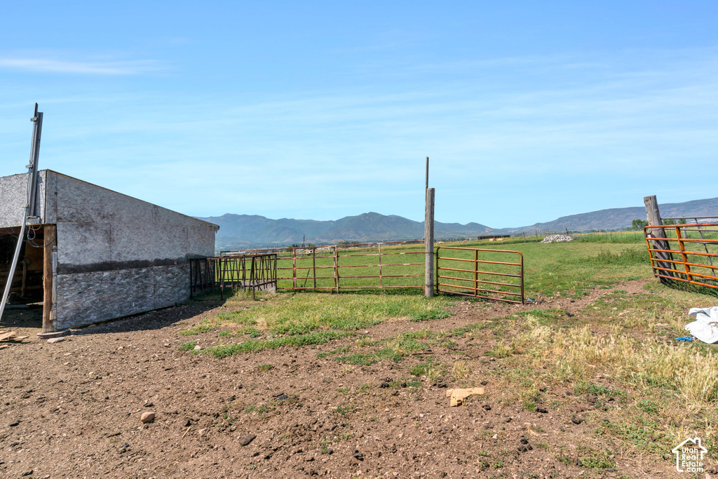 Barn structure with a metal roof, multiple fenced areas, expansive land, and mountain scenery