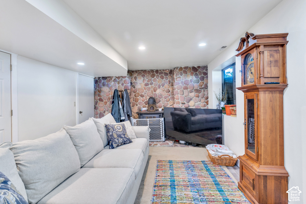 Recessed lighting, wood-finish flooring, stone accent wall, window, and white walls