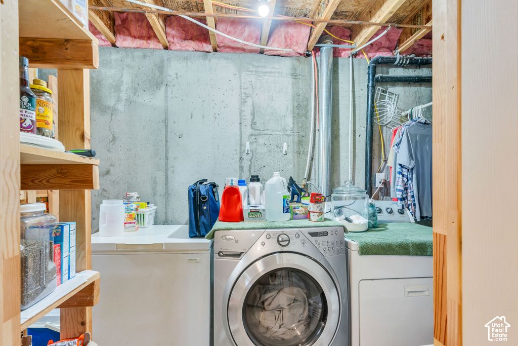 Utility area featuring a front-load washing machine, top-load dryer, and concrete walls