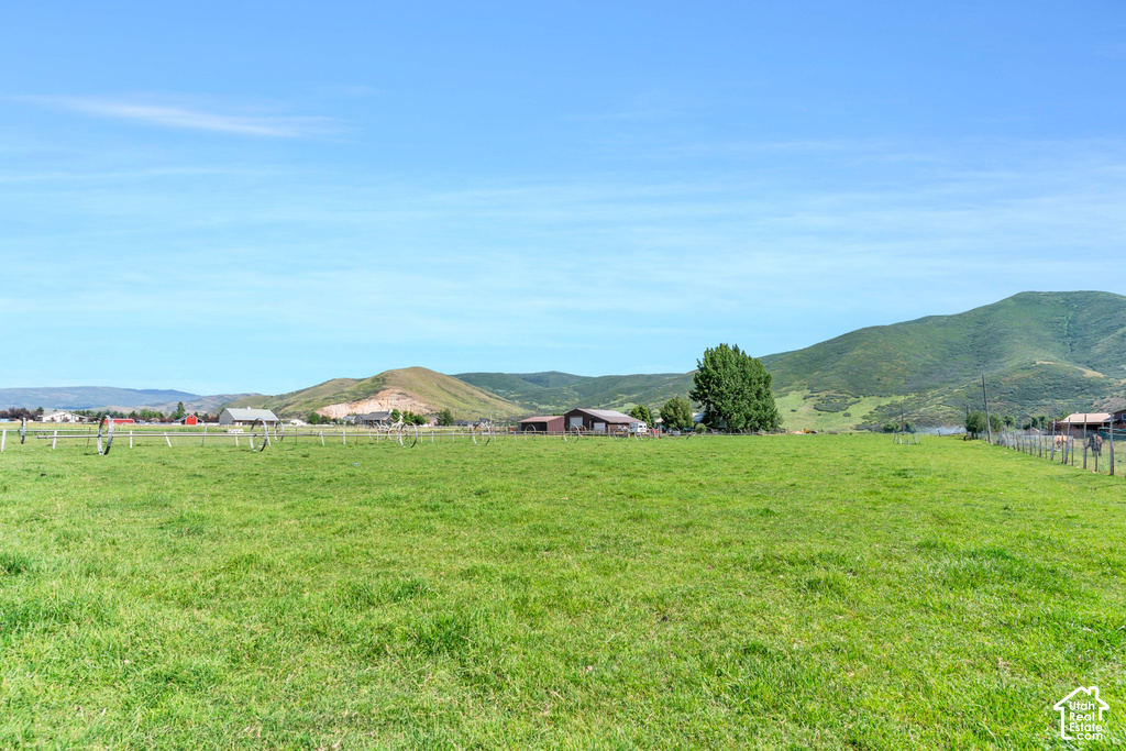 Expansive green pasture with a wood post fence, surrounded by rolling hills
