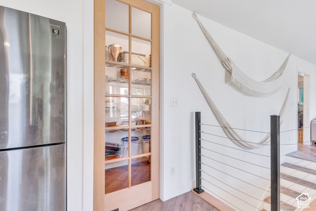Stainless steel refrigerator, wood-frame glass panel door, cable railing system, wood-finish flooring