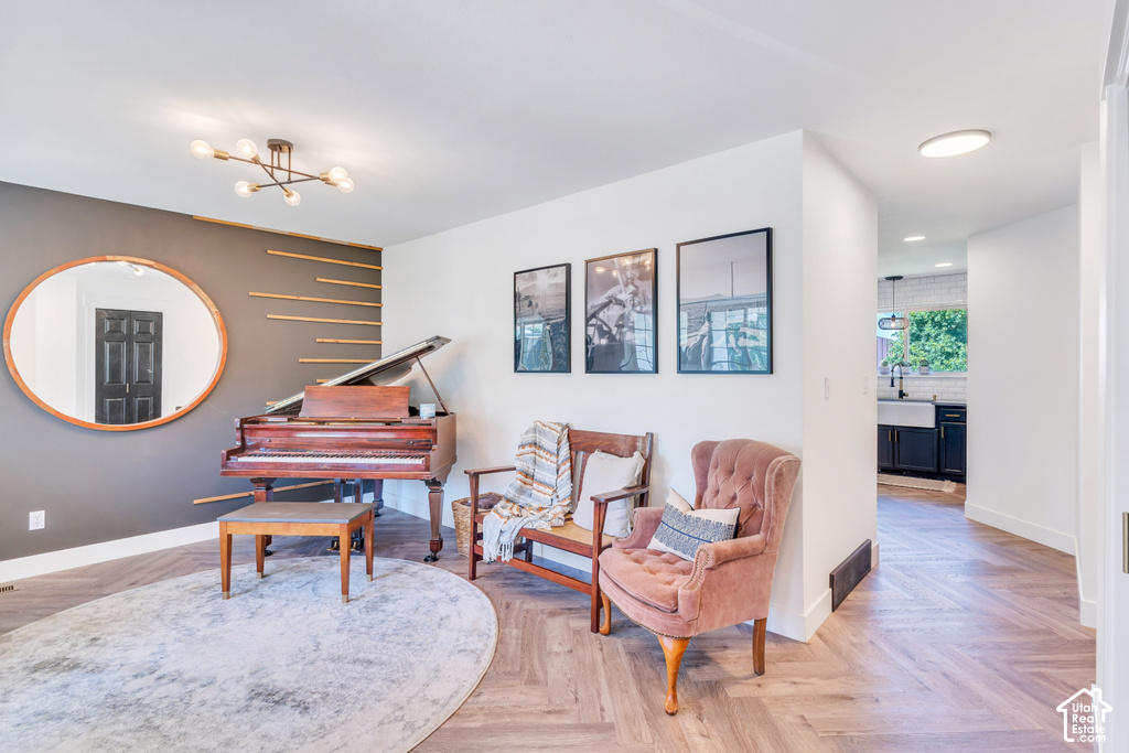 Herringbone-pattern wood-finish flooring, accent wall with decorative wood slats, contemporary ceiling light fixture, and recessed lighting