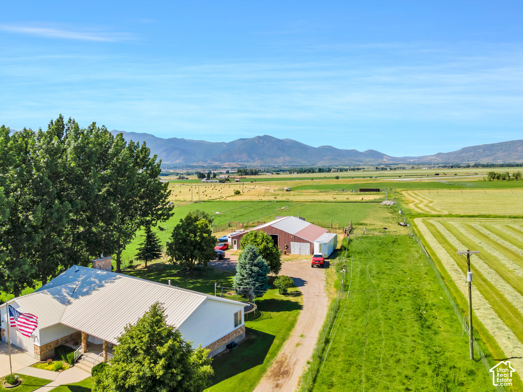 Expansive agricultural property featuring a primary residence with a metal roof, an additional barn structure, a gravel driveway, and cultivated fields