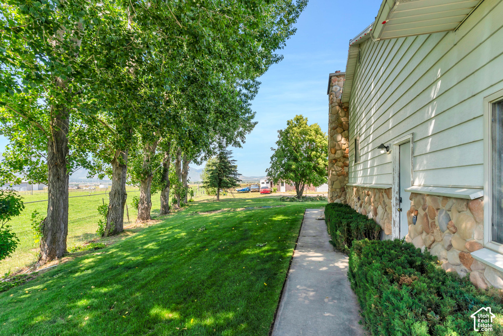 Siding exterior with a stone foundation, a concrete walkway, and a landscaped shrub border