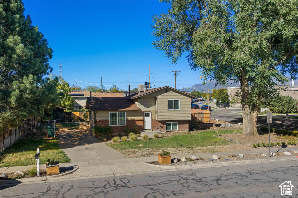Siding and brick exterior with a front entry, concrete driveway, front yard, and mature landscaping