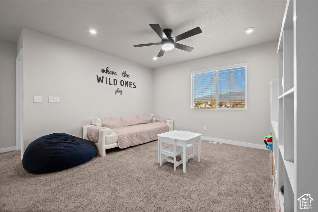 Spacious recreation room featuring neutral carpet flooring, recessed ceiling lighting, and a ceiling fan
