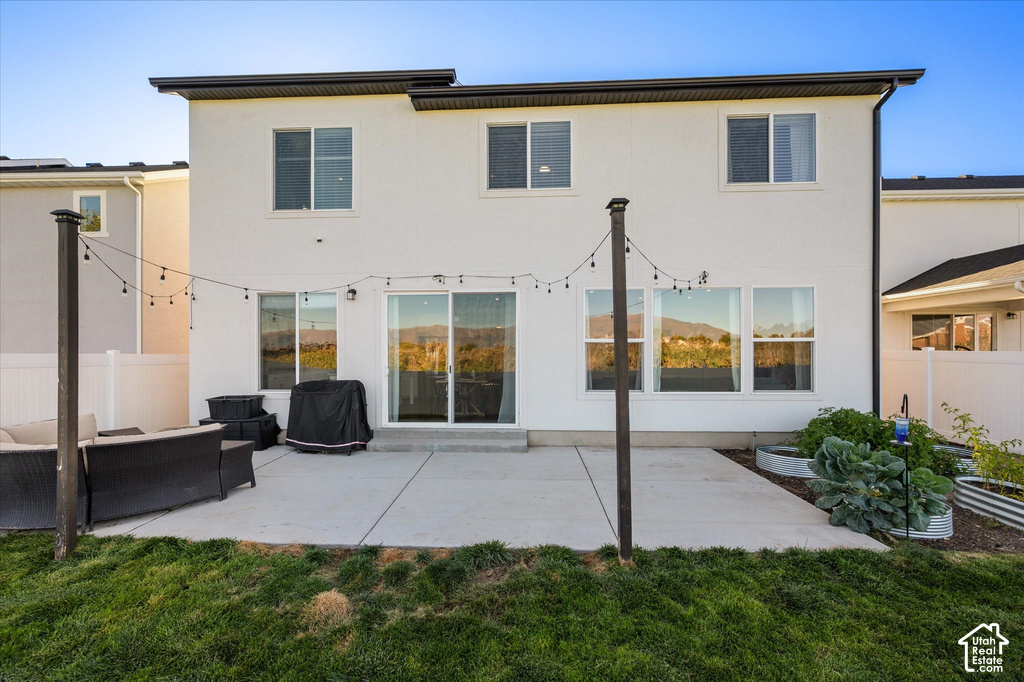 Rear exterior with a concrete patio, multiple windows, and a sliding glass door