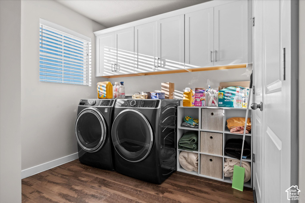 Laundry area featuring wood-finish flooring, white cabinetry with silver hardware, and a window with horizontal blinds