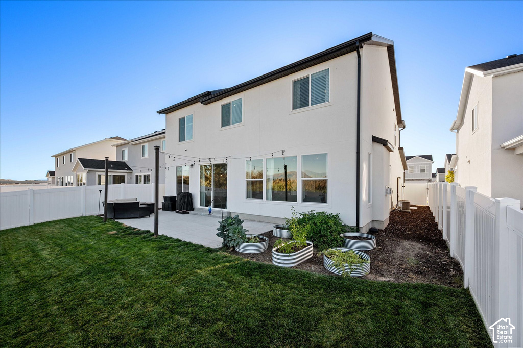 Expansive rear yard featuring a manicured lawn, concrete patio, and white vinyl fencing