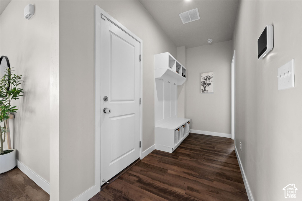 Wood-finish flooring, built-in storage bench, white interior door, light neutral wall color, and recessed ceiling lighting