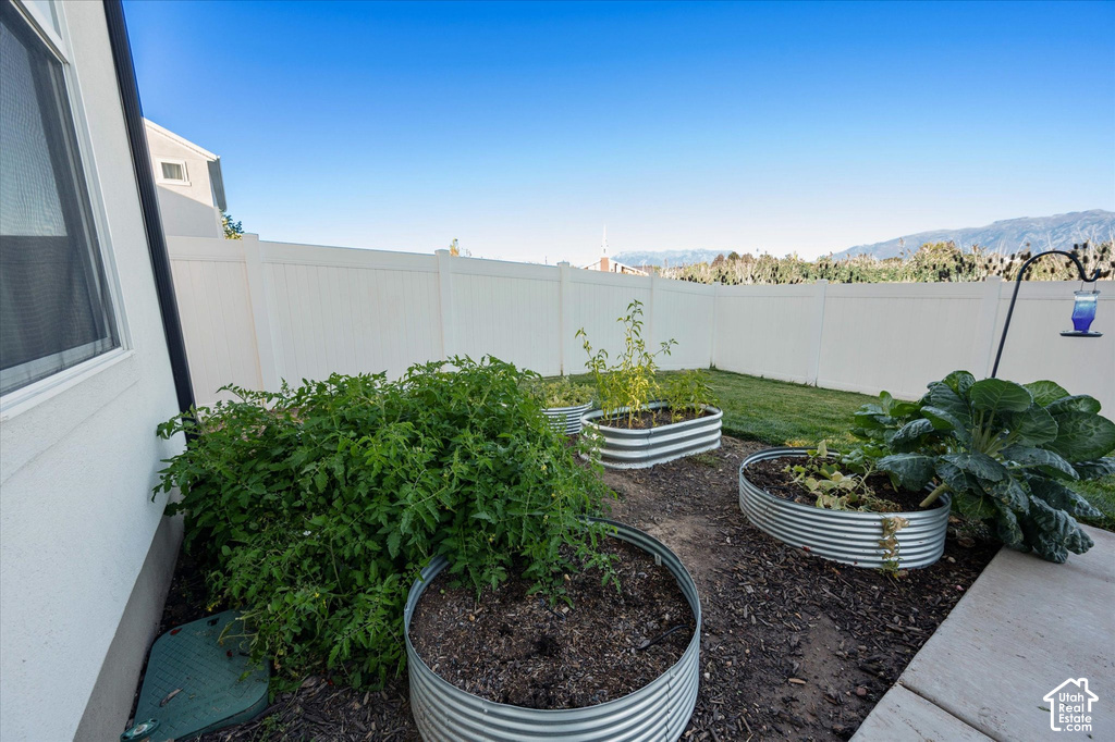 Backyard featuring a white privacy fence, three corrugated metal raised garden beds, a concrete patio section, and a manicured lawn area