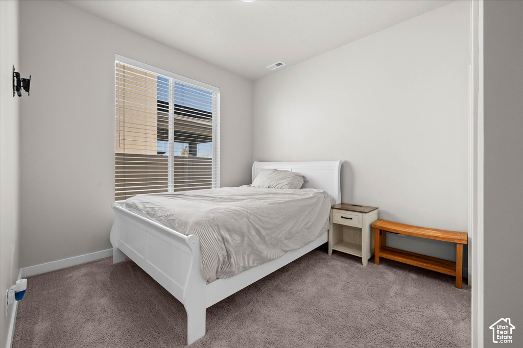 Carpeted room with a large window featuring horizontal blinds