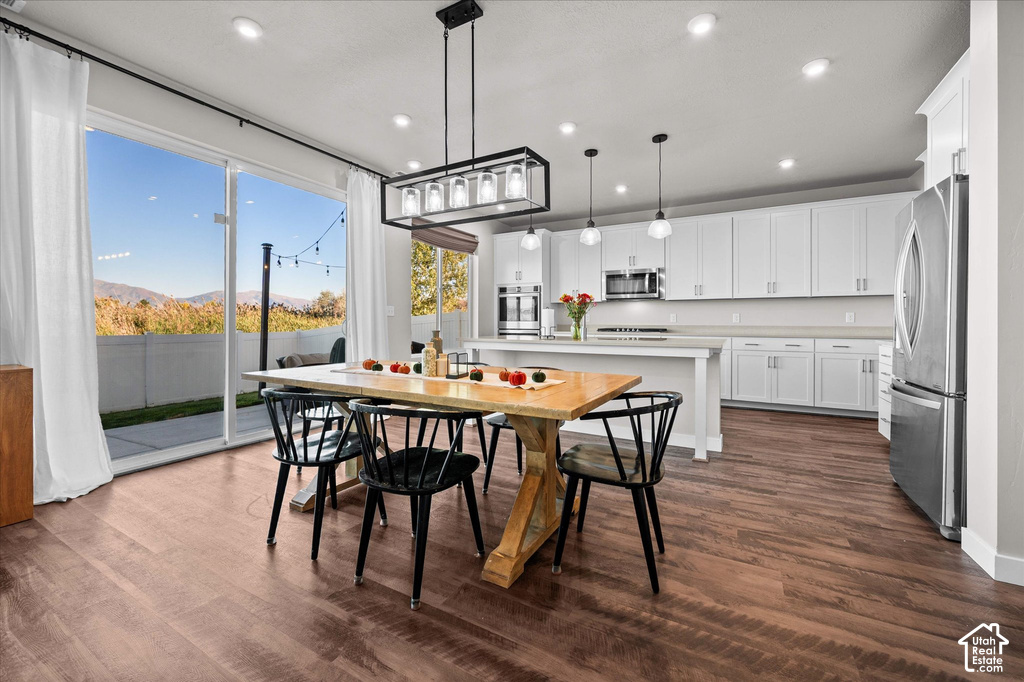 Open-concept living space with wood-finish flooring, white cabinetry, a kitchen island, and a sliding glass door