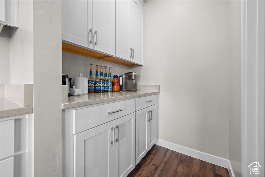 White shaker-style cabinetry with chrome pulls, light-toned countertop, wood-finish flooring, and open shelving