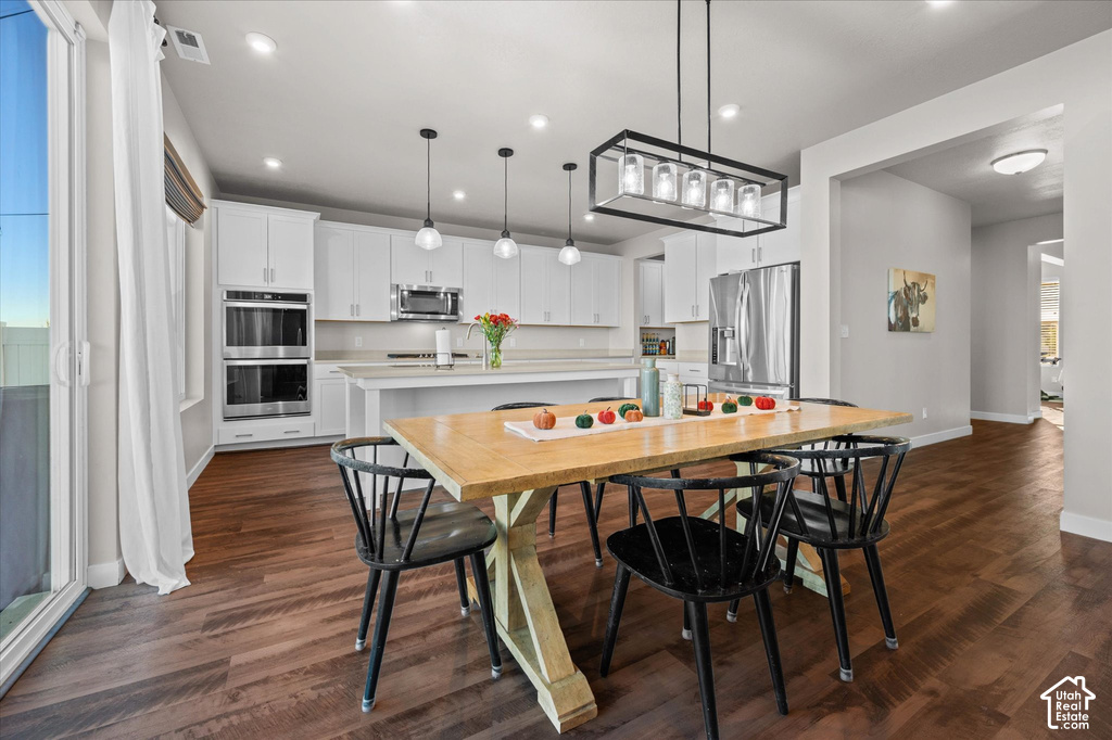 Wood-finish flooring throughout, featuring a kitchen with white cabinetry, stainless steel double ovens, and a kitchen island