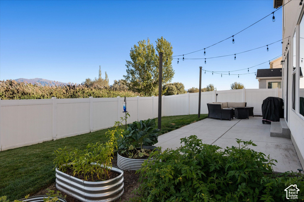 Expansive concrete patio with string lighting, surrounded by a white privacy fence