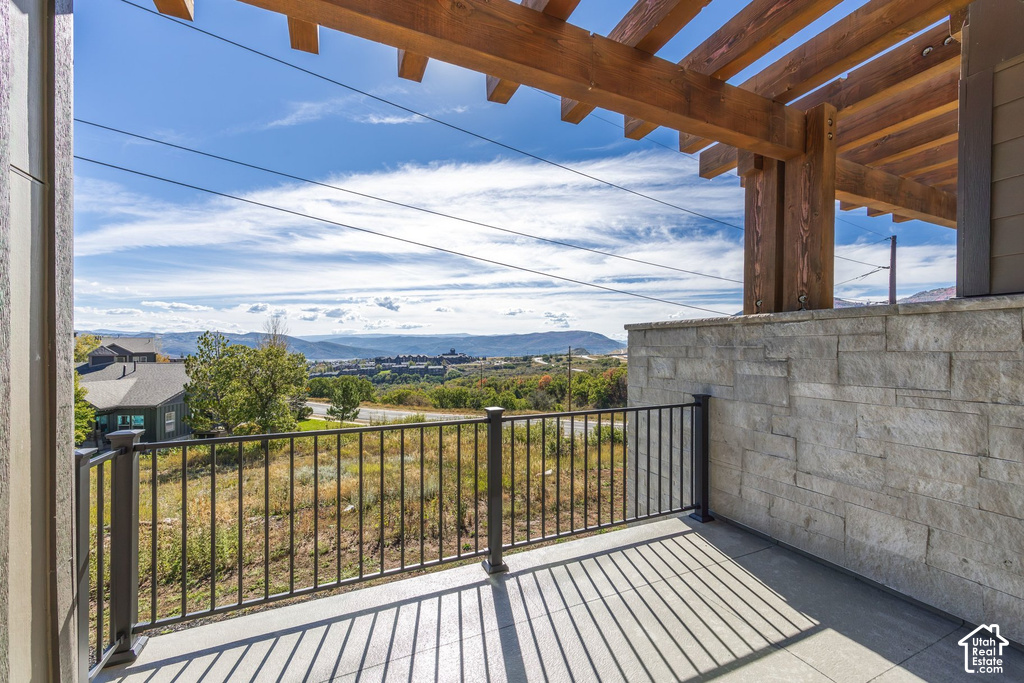 Outdoor patio with wood pergola, stone-clad wall, and metal railing