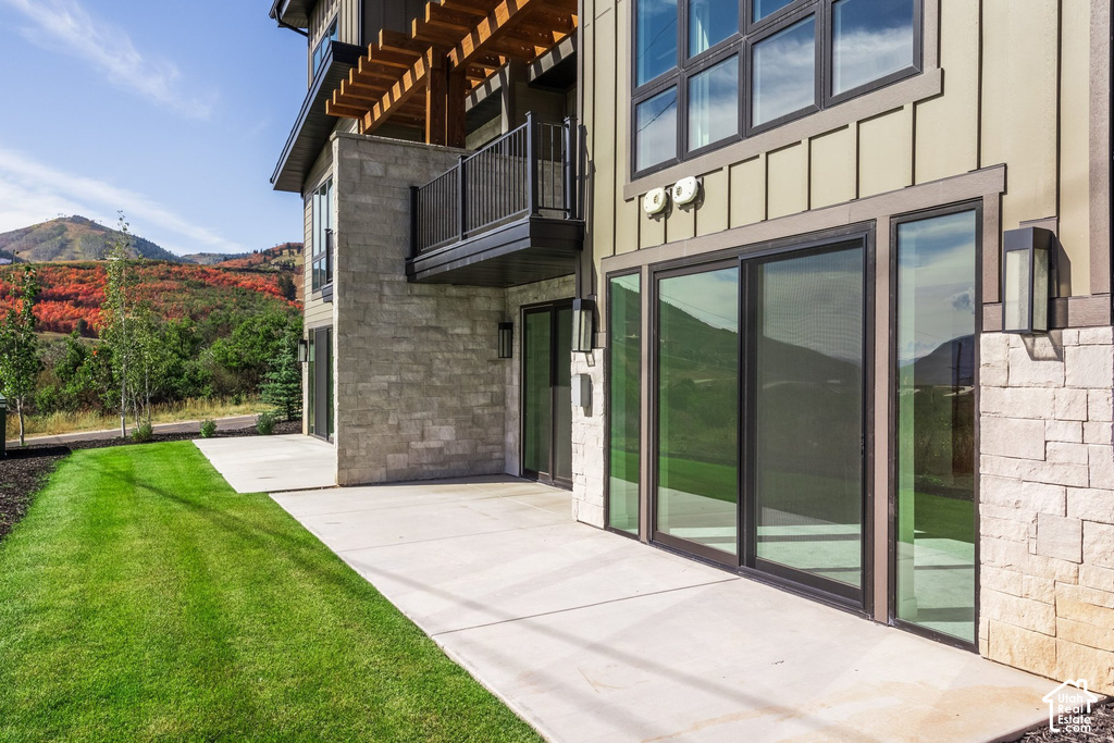 Expansive patio with direct lawn access, featuring multi-panel sliding glass doors and stacked stone accents