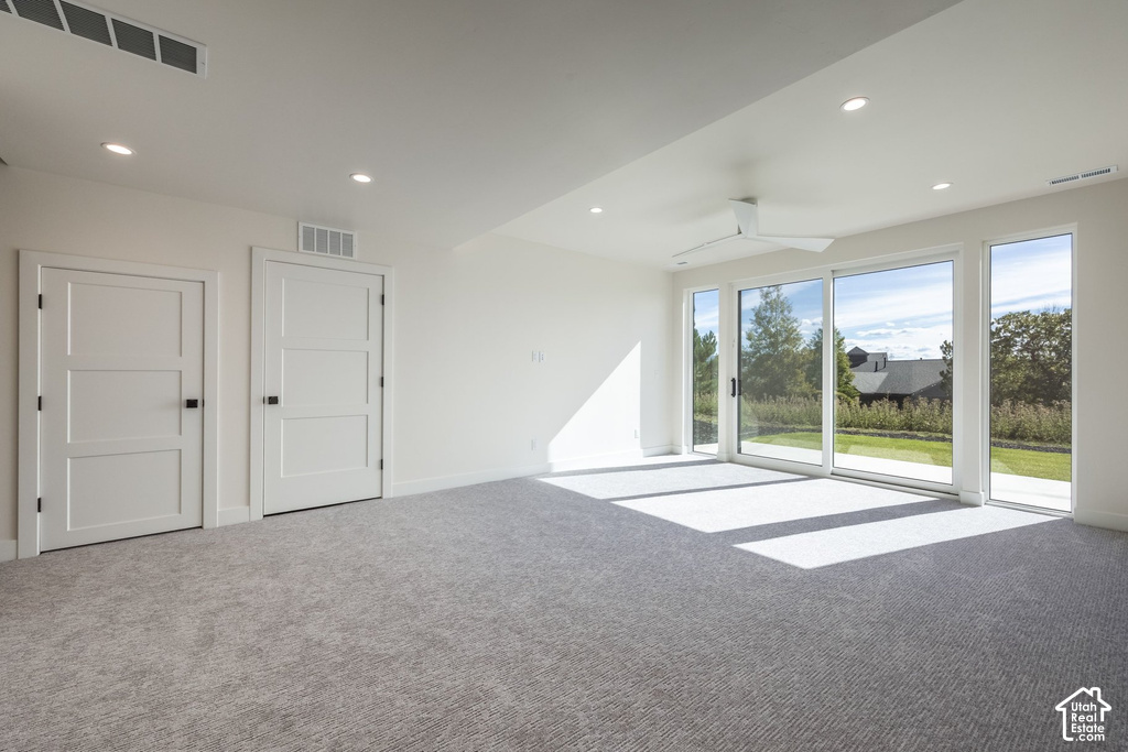 Spacious room featuring light gray carpet, recessed lighting, and a modern ceiling fan