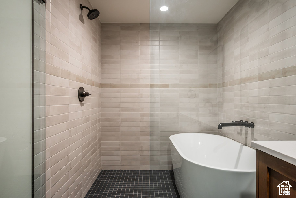 Glass-enclosed shower with matte black fixtures, subway tile walls, and dark tile flooring