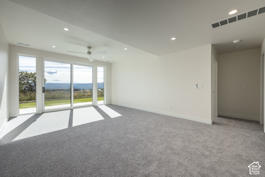 Sliding glass doors, recessed lighting, ceiling fan, and grey carpeting