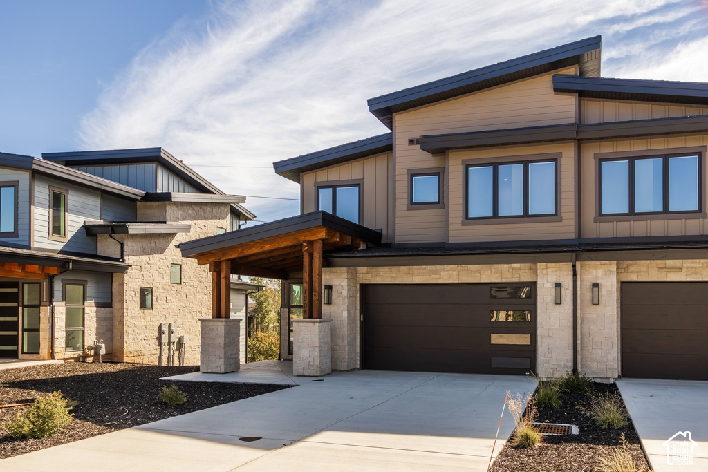 Contemporary architecture featuring multi-tone siding, stone accents, and dark-framed windows