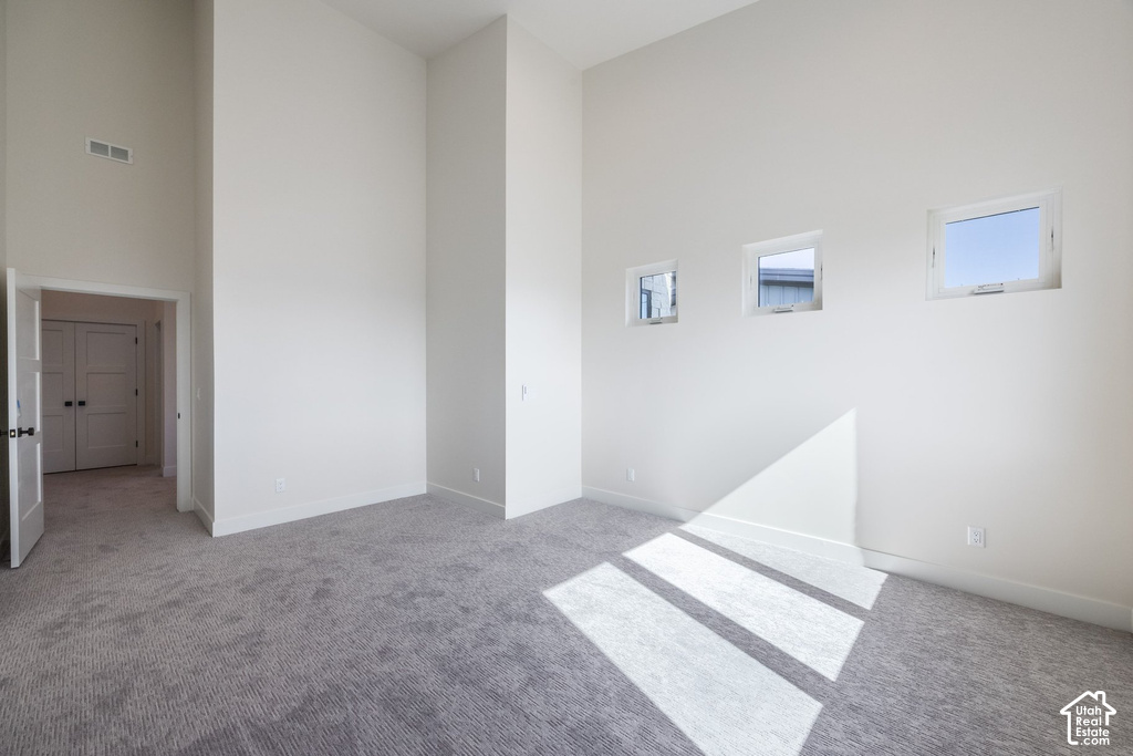 Soaring ceilings with recessed lighting, three upper-level windows, light gray carpeting, and white trim