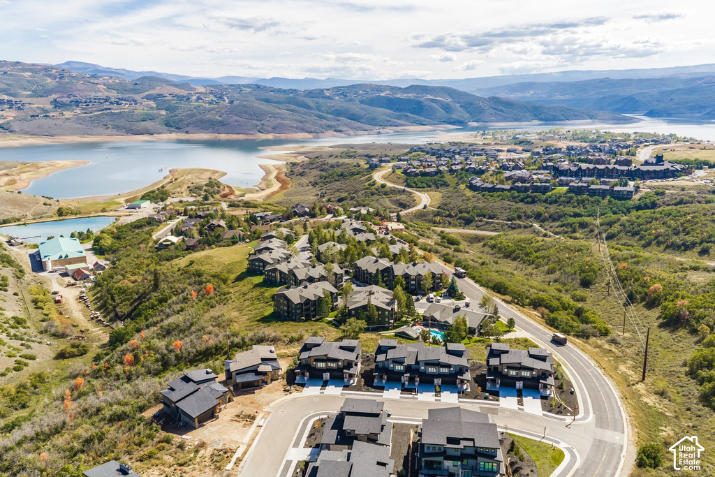 Expansive hillside development with multiple residential structures, winding paved roadways, and a prominent lake in the background