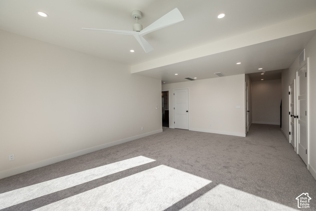 Recessed ceiling lighting, modern ceiling fan, light gray carpeting, white interior doors with black hardware, and light-colored walls